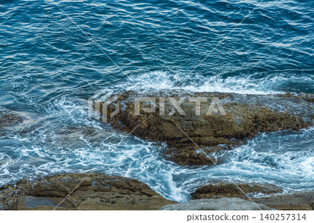 The blue sea with waves crashing against the shore and the rugged rocky landscape The blue sea with waves crashing against the shore and the rugged rocky landscape 140257314