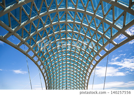 Modern Pedestrian Bridge with Futuristic Steel Structure and Glass Elements Modern Pedestrian Bridge with Futuristic Steel Structure and Glass Elements 140257556