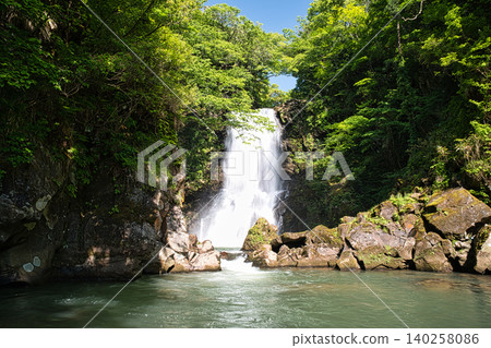 The magnificent view of Naso no Shirataki waterfall roaring down into the beautiful, lush green valley. The magnificent view of Naso no Shirataki waterfall roaring down into the beautiful, lush green valley. 140258086