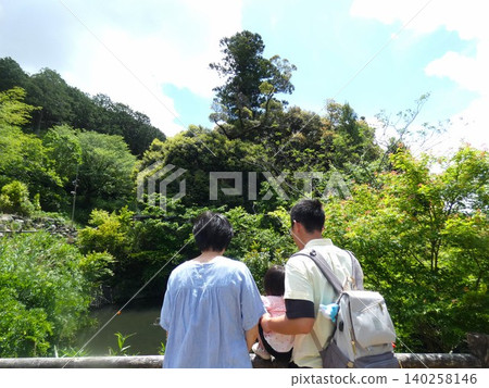 A girl and her parents watching the carp in the pond at Akaiwa Temple in Toyohashi City. A girl and her parents watching the carp in the pond at Akaiwa Temple in Toyohashi City. 140258146