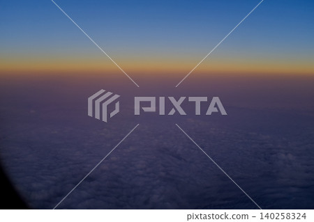 Looking through the airplane window with the sunset sky. Romantic sky, golden hours, colorful sunset sky with clouds. Stunning cloudscape and skyscape. Nature concept. For background use. Looking through the airplane window with the sunset sky. Romantic sky, golden hours, colorful sunset sky with clouds. Stunning cloudscape and skyscape. Nature concept. For background use. 140258324