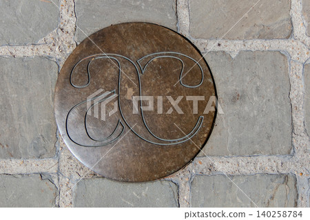 Bronze commemorative medallion with AC monogram on cobblestone pavement Bronze commemorative medallion with AC monogram on cobblestone pavement 140258784