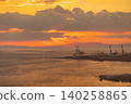 Dramatic sunset over a busy industrial port with cranes and calm water 140258865