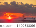 Vibrant sunset over the ocean with industrial cranes and distant mountains 140258866