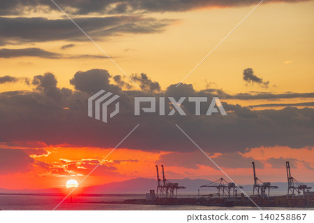 Dramatic sunset over industrial port with cranes and fiery clouds 140258867