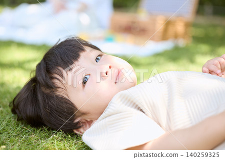 A little boy lying on the grass, looking up at the sky. A little boy lying on the grass, looking up at the sky. 140259325