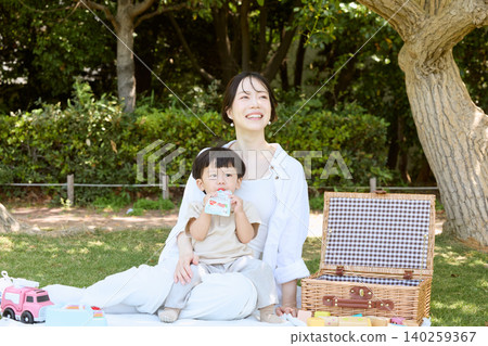 一位母親和她的幼兒在公園裡享受野餐。 一位母親和她的幼兒在公園裡享受野餐。 140259367
