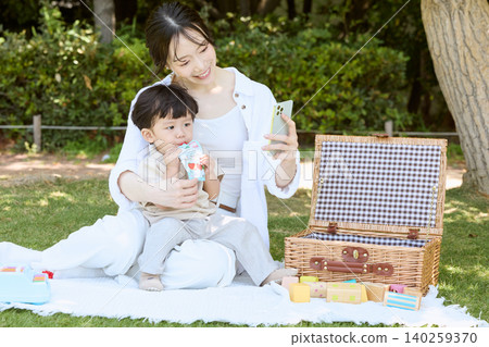 一對母子在公園野餐時用智慧型手機自拍。 一對母子在公園野餐時用智慧型手機自拍。 140259370