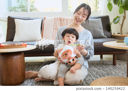 一位微笑的母親在客廳給孩子刷牙。 一位微笑的母親在客廳給孩子刷牙。 140259422