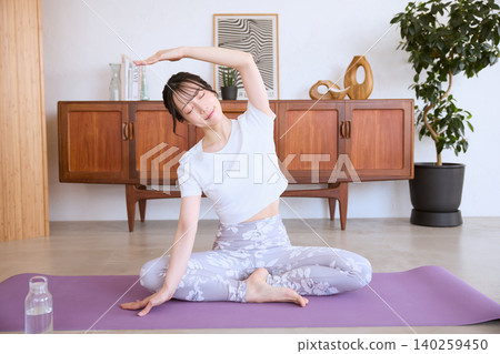 A young woman doing yoga stretches in her living room at home. 140259450