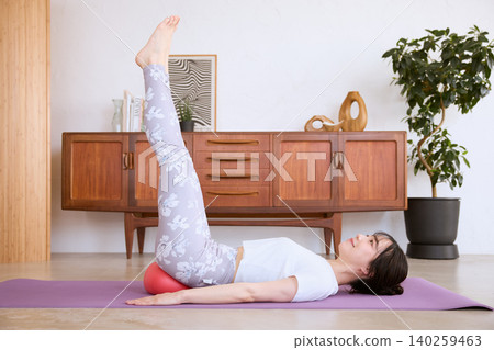 A woman doing leg raises at home using a balance ball. 140259463