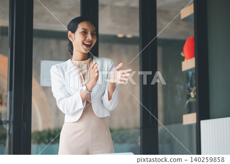 Laughing businesswoman standing and applauding in office, celebrating project success, team achievement and positive feedback after a presentation in a modern professional workplace. Laughing businesswoman standing and applauding in office, celebrating project success, team achievement and positive feedback after a presentation in a modern professional workplace. 140259858