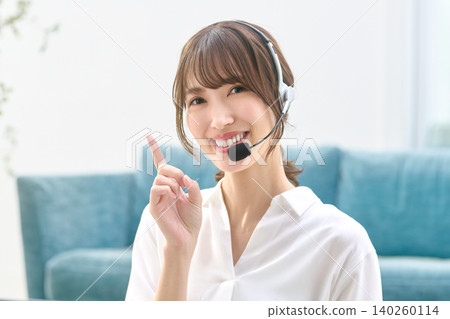 A smiling woman wearing a headset gives directions by pointing. 140260114
