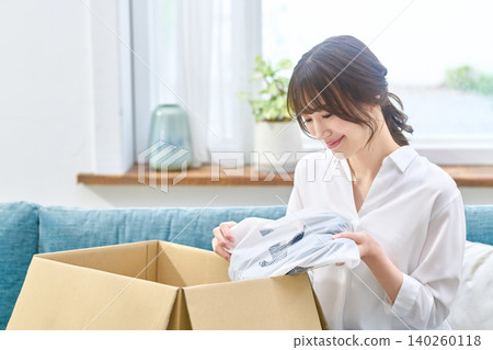 A woman opens a cardboard box and checks the delivered goods. A woman opens a cardboard box and checks the delivered goods. 140260118