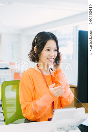 A female operator wearing a headset answers calls in the office. A female operator wearing a headset answers calls in the office. 140260419