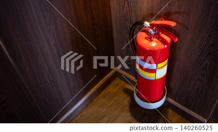 Red tank of fire extinguisher placed at the corner of wooden corridor in public building Red tank of fire extinguisher placed at the corner of wooden corridor in public building 140260525
