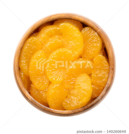Canned mandarin oranges, in a wooden bowl. Peeled, seedless, whole segments, packed in light sugar syrup. Ripe, bright orange, small and rounded fruits of Citrus reticulata. Isolated from above. Photo 140260649