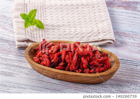 Organic dried goji berries in wooden bowl with fresh mint leaf Organic dried goji berries in wooden bowl with fresh mint leaf 140260739