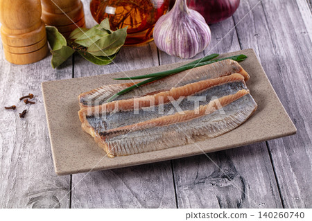 Pickled herring fillets on ceramic plate with spices and garlic on wooden table Pickled herring fillets on ceramic plate with spices and garlic on wooden table 140260740