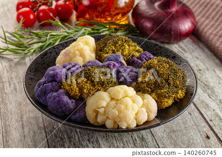Colorful cauliflower and broccoli florets on dark plate with vegetables Colorful cauliflower and broccoli florets on dark plate with vegetables 140260745