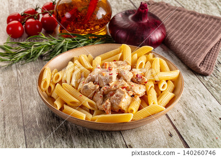 Penne pasta with creamy chicken sauce and spices in rustic ceramic bowl on wooden table Penne pasta with creamy chicken sauce and spices in rustic ceramic bowl on wooden table 140260746
