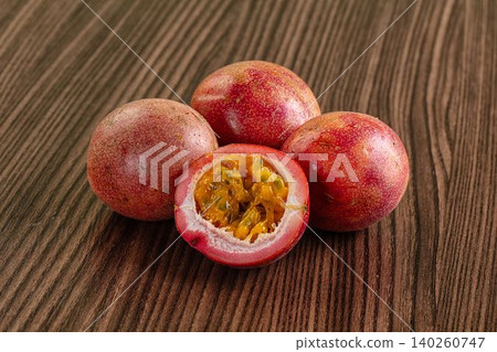 Fresh passion fruit on wooden table with cut half showing pulp Fresh passion fruit on wooden table with cut half showing pulp 140260747