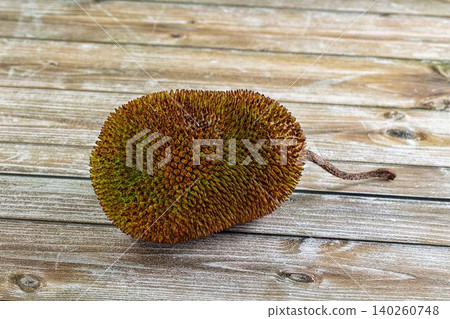Ripe jackfruit with spiky green and brown skin on rustic wooden background Ripe jackfruit with spiky green and brown skin on rustic wooden background 140260748