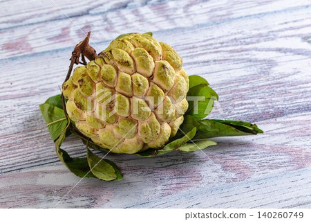 Fresh custard apple fruit with green leaves on wooden background Fresh custard apple fruit with green leaves on wooden background 140260749