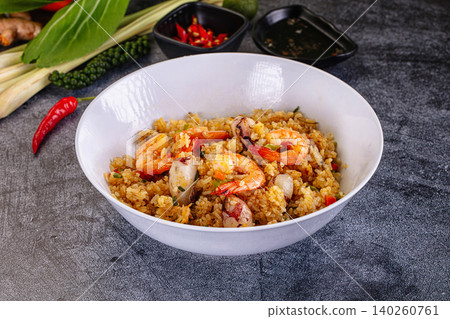 Thai fried rice with shrimp and squid in white bowl on dark stone background with fresh ingredients Thai fried rice with shrimp and squid in white bowl on dark stone background with fresh ingredients 140260761