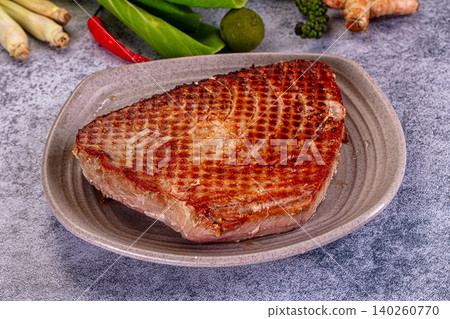 Grilled tuna steak with grill marks on plate surrounded by fresh ingredients Grilled tuna steak with grill marks on plate surrounded by fresh ingredients 140260770