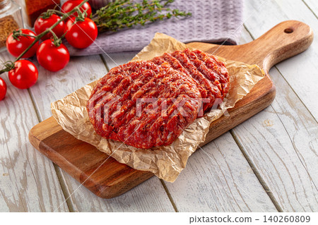 raw beef burger patties on wooden board with tomatoes and thyme raw beef burger patties on wooden board with tomatoes and thyme 140260809