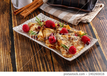 Crepes with fresh raspberries, cranberries, rosemary on rustic wooden table Crepes with fresh raspberries, cranberries, rosemary on rustic wooden table 140260816