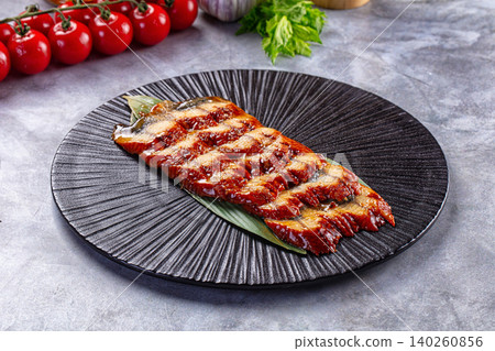 Grilled eel fillet on black plate with cherry tomatoes Grilled eel fillet on black plate with cherry tomatoes 140260856