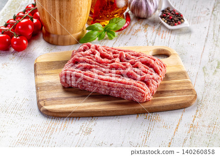 Raw minced meat on wooden board with fresh ingredients Raw minced meat on wooden board with fresh ingredients 140260858