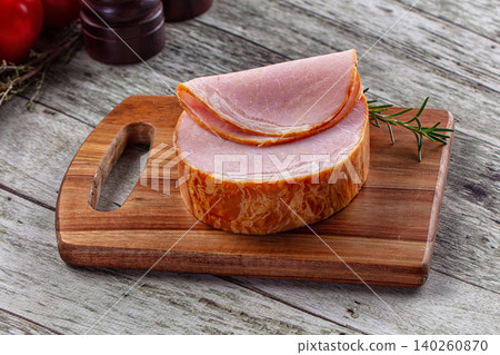 Sliced ham on wooden cutting board with rosemary 140260870