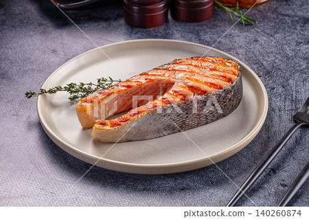 Grilled salmon steak on ceramic plate with herbs 140260874