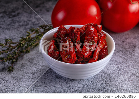 Sun-dried tomatoes in white bowl with fresh thyme and ripe tomatoes on gray stone background Sun-dried tomatoes in white bowl with fresh thyme and ripe tomatoes on gray stone background 140260880