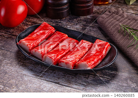 Crab sticks on black plate with tomatoes and rosemary Crab sticks on black plate with tomatoes and rosemary 140260885
