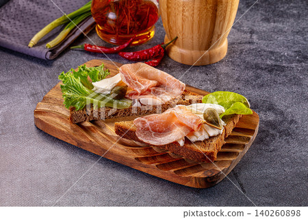 Open sandwich with prosciutto, cheese, and lettuce on wooden board Open sandwich with prosciutto, cheese, and lettuce on wooden board 140260898