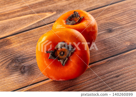 Two ripe persimmons on rustic wooden background Two ripe persimmons on rustic wooden background 140260899