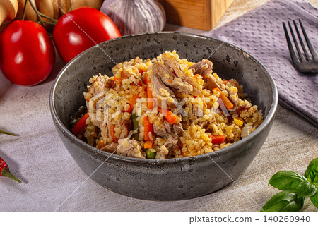 Hearty pilaf with meat and vegetables in a rustic ceramic bowl Hearty pilaf with meat and vegetables in a rustic ceramic bowl 140260940