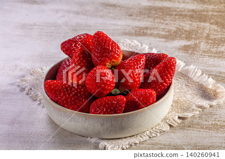 Fresh ripe strawberries in a rustic ceramic bowl on a light table 140260941