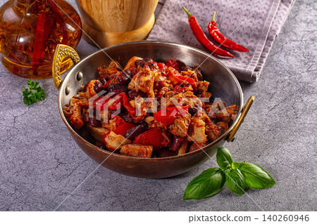 Hearty meat and red bean stew in a rustic bowl with chili peppers and basil Hearty meat and red bean stew in a rustic bowl with chili peppers and basil 140260946