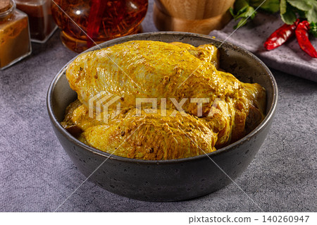 Raw chicken thighs marinated in yellow curry sauce in a rustic bowl Raw chicken thighs marinated in yellow curry sauce in a rustic bowl 140260947
