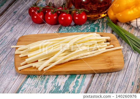 String cheese sticks on wooden cutting board with fresh vegetables 140260976
