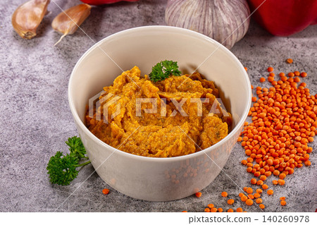 Red lentil dip in white bowl with parsley and garlic on stone background Red lentil dip in white bowl with parsley and garlic on stone background 140260978