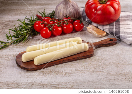 Fresh mozzarella cheese sticks on wooden board with tomatoes and rosemary Fresh mozzarella cheese sticks on wooden board with tomatoes and rosemary 140261008