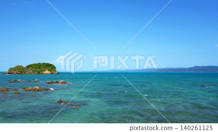 Coastal scenery of Yagaji Fishing Port in Okinawa: Emerald green sea, rocky reefs, and blue sky. 140261125