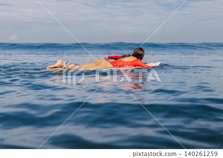 Surfer girl on surfboard. Attractive woman during surfing 140261259