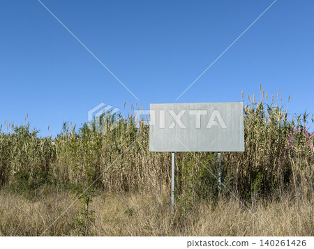 Blank signboard in dry grass under a clear blue sky 140261426